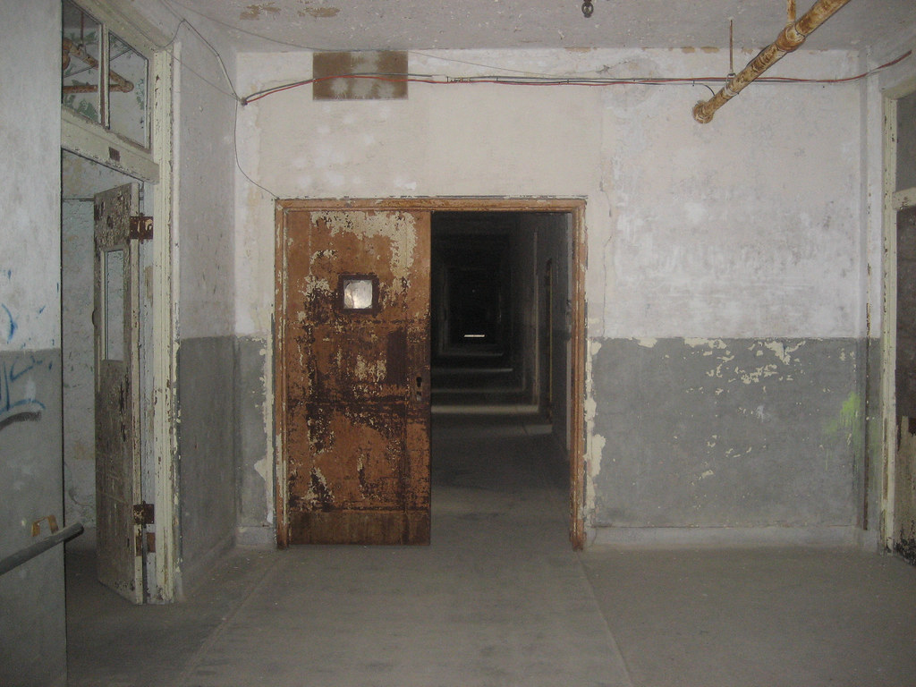 photo shows a waverly hills sanatorium hallway at nighttime. the photo shows a rusty doorway