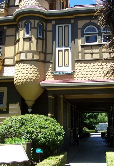 photo shows the outside of the winchester house with a painted door about 10 feet up on the side of the house