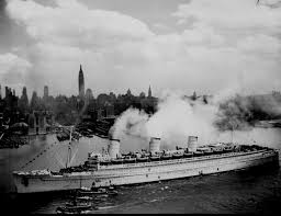 photo shows the rms queen mary in the new york harbor, the photo is black and white and has the queen mary in the foreground with steam coming out of it and the nyc skyline in the back
