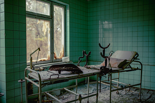 photo shows an old hospital surgical bed sitting, abandoned and dusty.