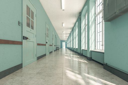 photo shows the hallway in a mental hospital, the walls are aqua and the right wall is lined with windows.