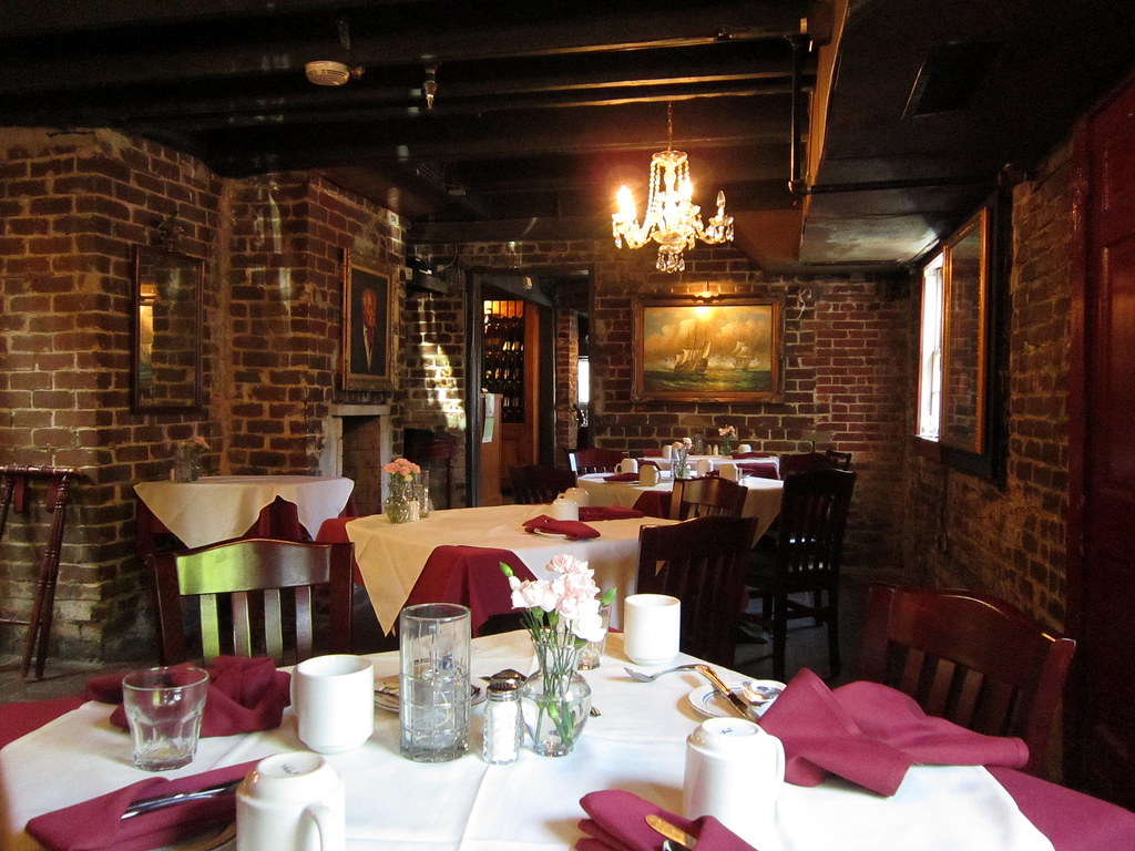 photo shows the inside of the restaurant area of the 17hundred90 inn, with red napkins and dark brick walls