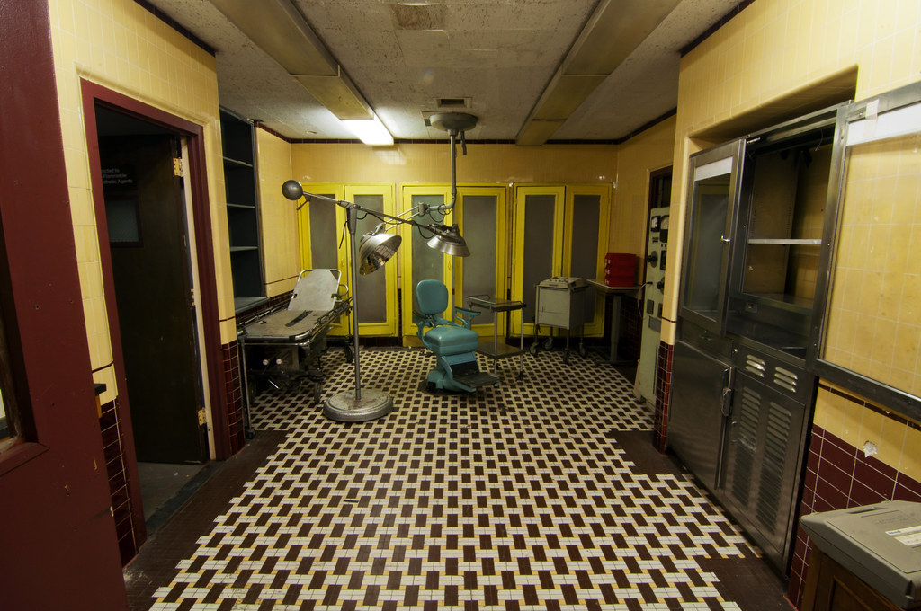 photo shows a patient room in linda vista, there is a checkered tile floor and an old doctor's chair with a light above it