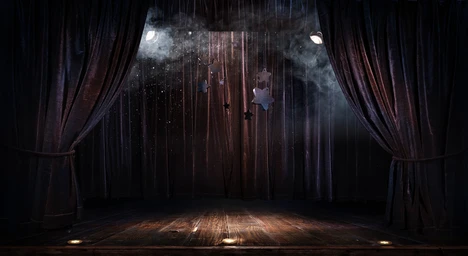 photo shows an empty stage with fog and red velvet curtains