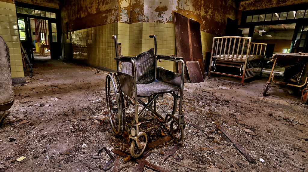 photo shows the inside of forest haven, the floor is covered in debris and there sits an abandoned wheelchair