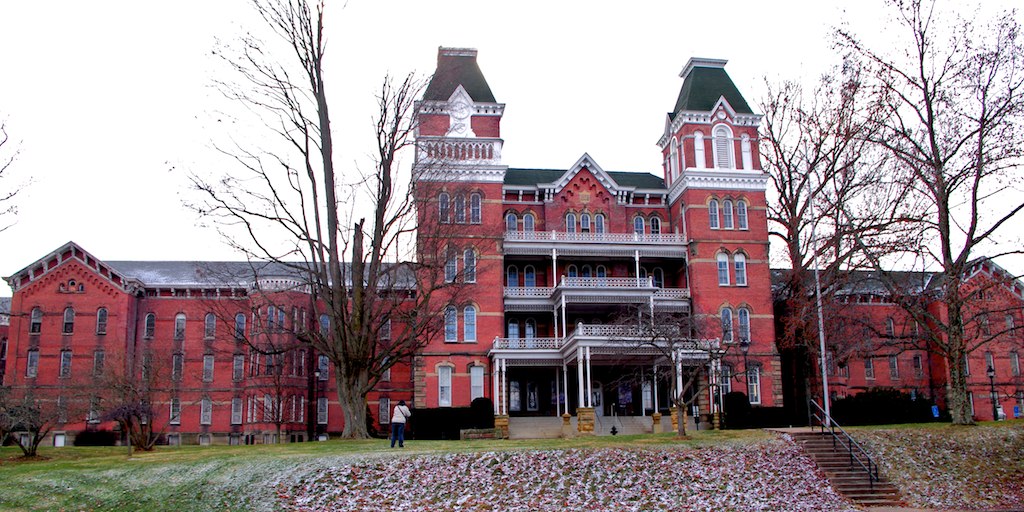 photo shows the athens mental hospital, its got three story balconies and towers in the front