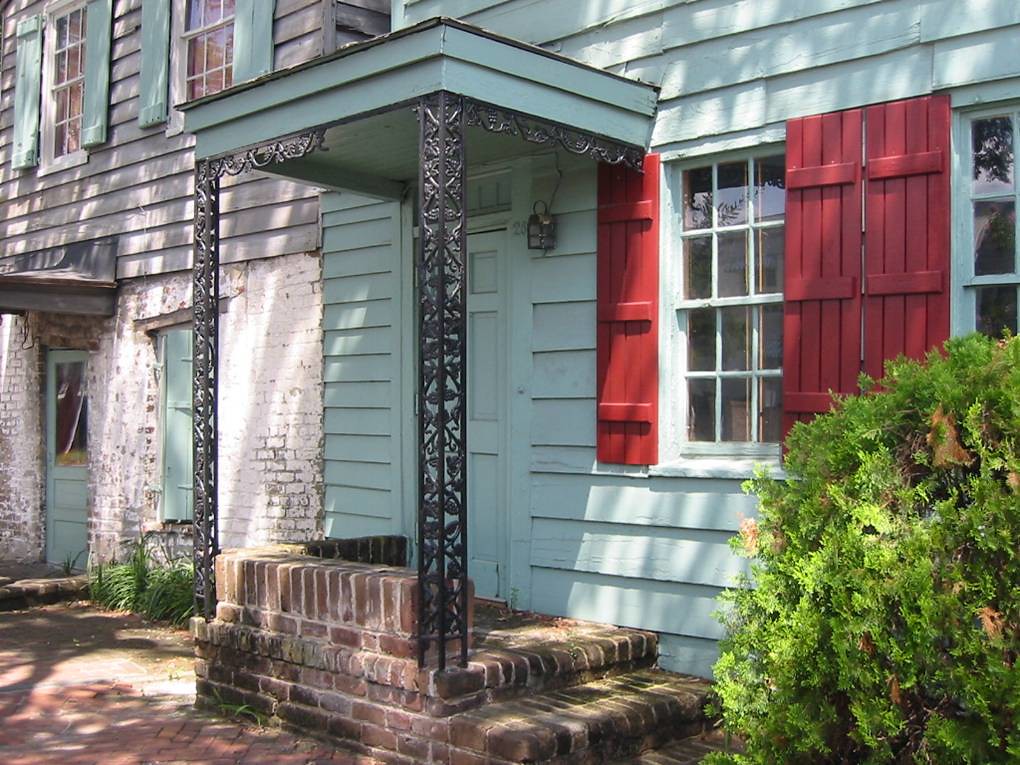 photo shows a house front painted a very light blue with red shutters
