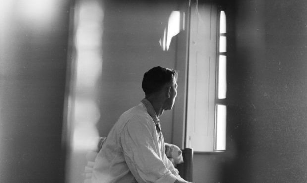 photo shows a doctor sitting looking out of a window. he is in a white labcoat