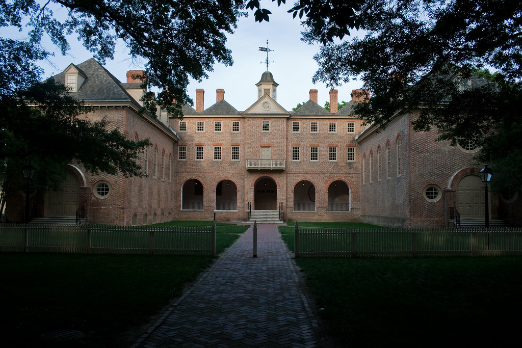 photo shows a dark shot of the main building on campus, surrounded by trees