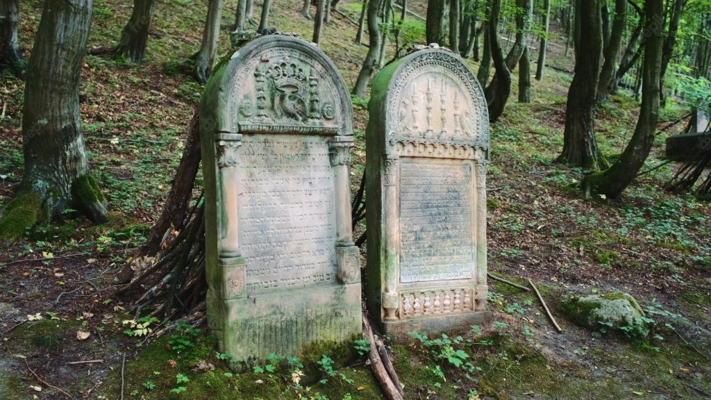 photo shows two weathered headstones in a forested area
