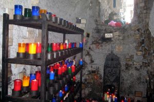 A collection of candles on shelves next to a shrine of a saint