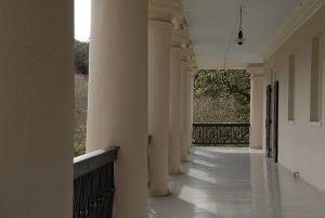 Image shows a portico with a row of tall, thick columns flanking the left side