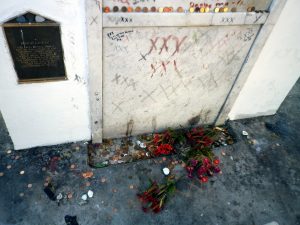 St. Louis Cemetery. Flowers, coins lay at the bottom a limestone tomb