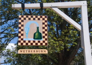 Sign with checkered pattern and antique green bottle with the words Wetherburn beneath it