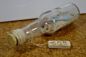 photo shows a small glass bottle with an sos tag attached