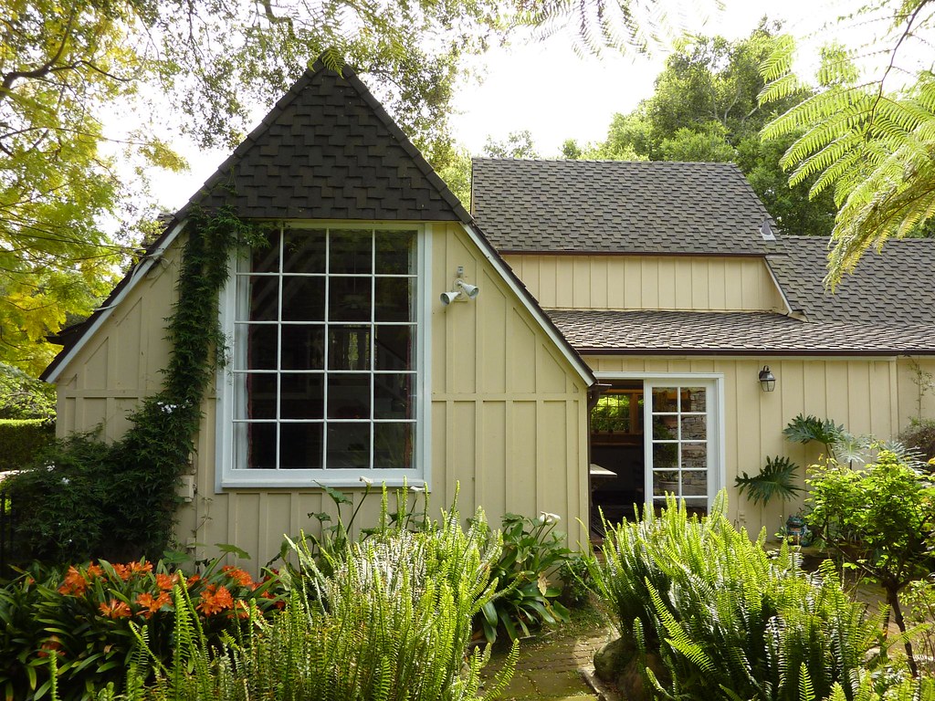 A Yellow Cottage Behind A Fern Filled Garden