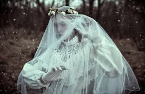 Darkened photo of woman in white wedding dress with veil 