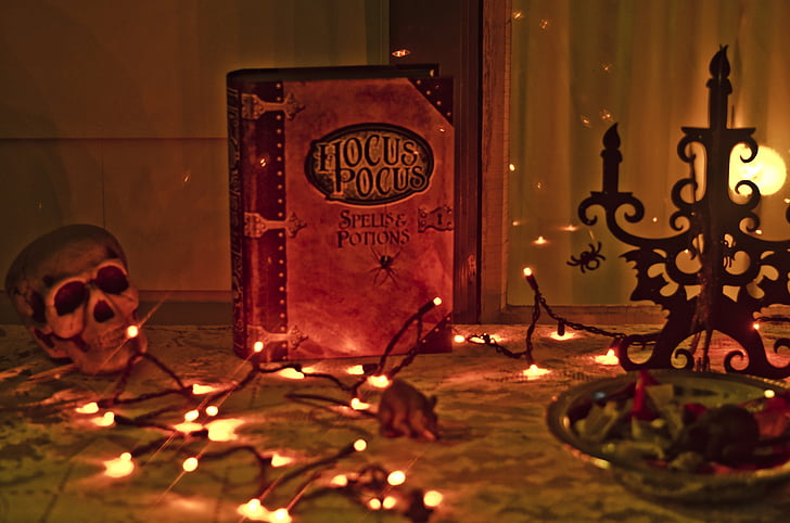 A book reading "Hocus Pocus" Spells & Potions sits atop a lit tables