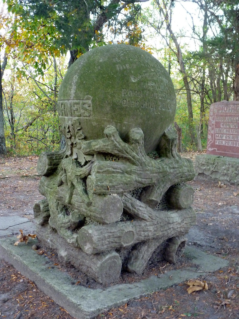 A tombstone shaped as a pile of woods with a crystal ball on top