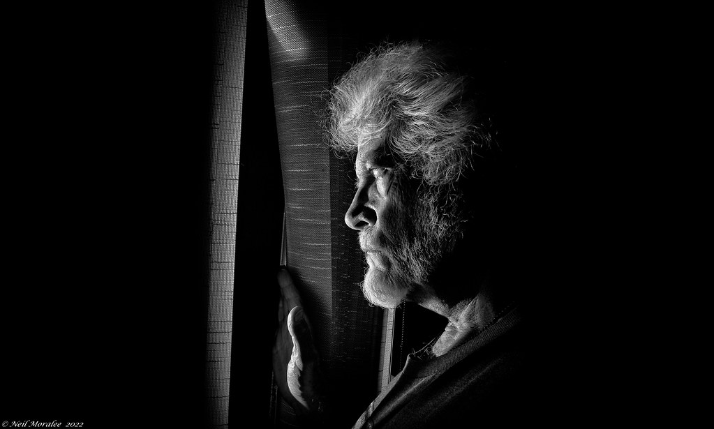 photo shows an older man looking out of a window
