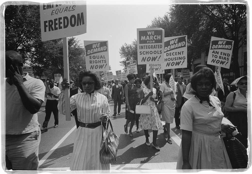 13th Amendment. American Men and Women crowd a street holding signs demanding freedom and integrated schools. 