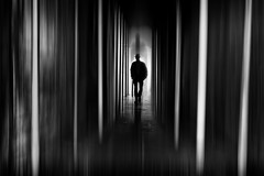 Photo of a dark hallway and the silhouette of a person at the end. 