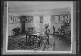 A black and white photo of a parlor room with a table in the center. 