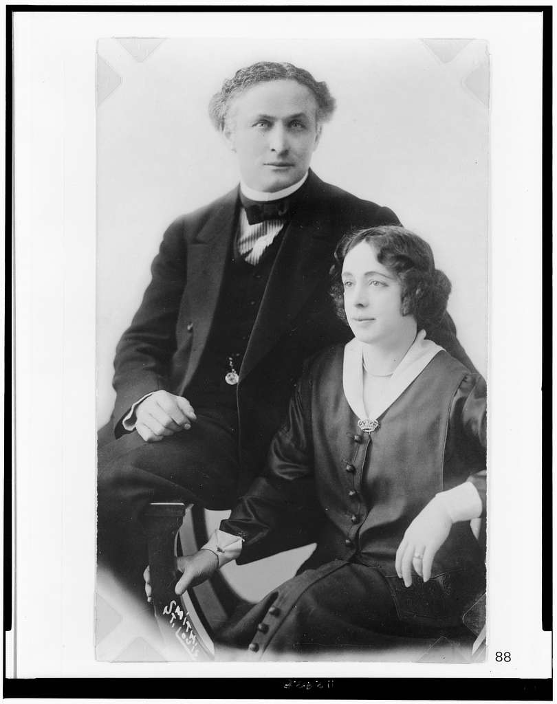 A black and white photo of Harry Houdini and his Wife Bess. Both wearing formal attire from the turn of the century