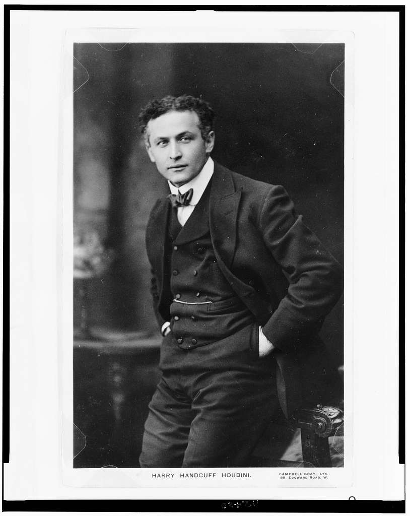 Black and white photo of Harry Houdini. Wearing a suit with his hands behind his back