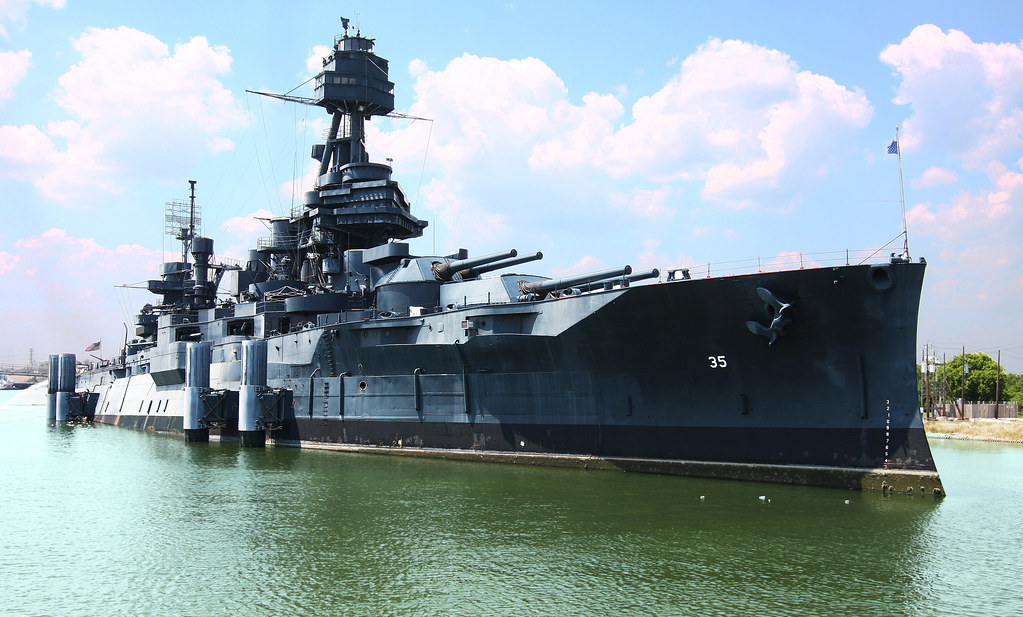 A large battleship sits atop green blue water