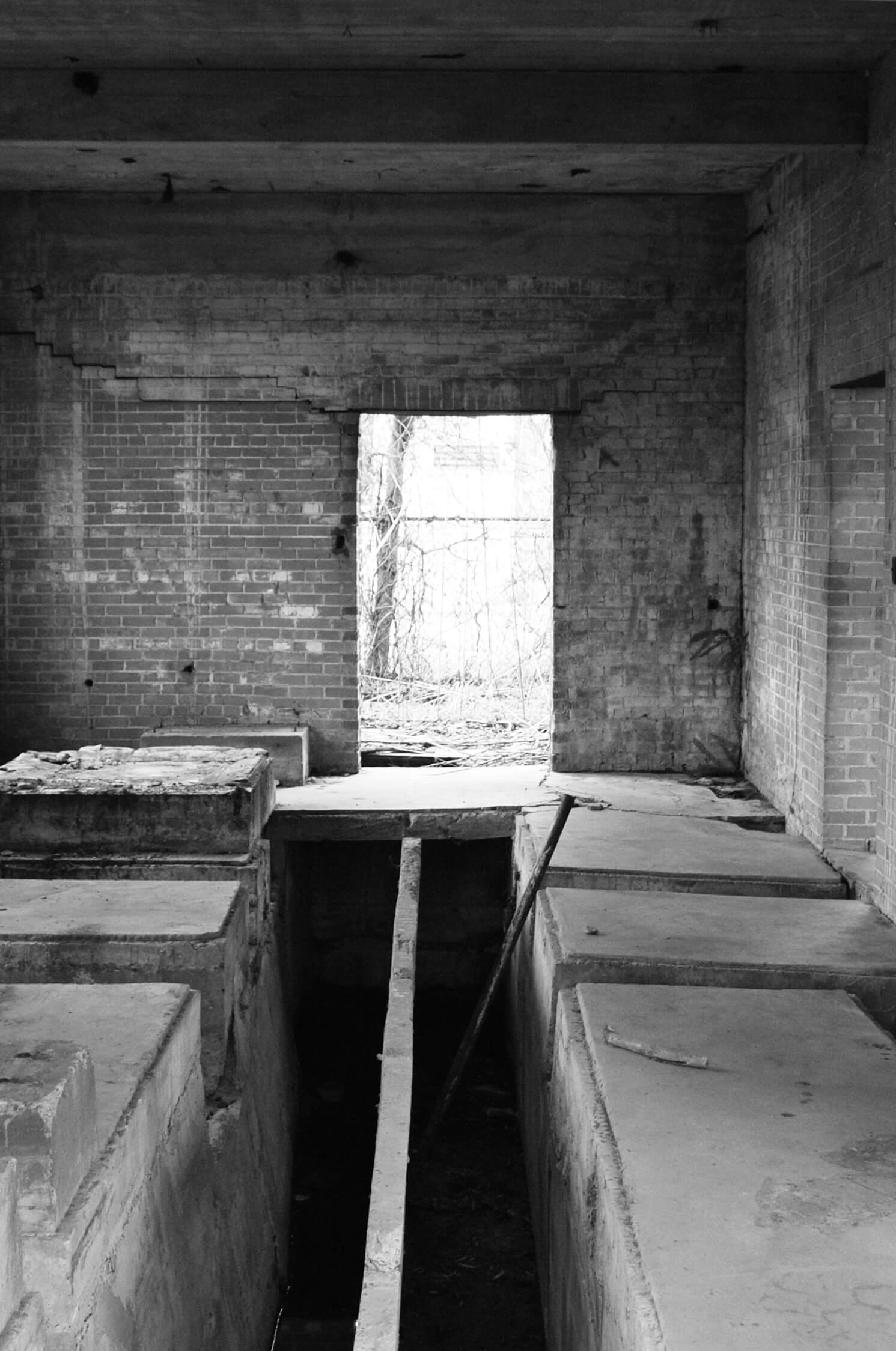 A black and white photo of a brick room with one window