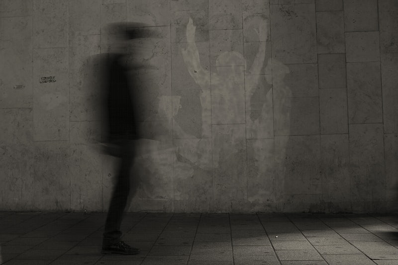 A shadow man walking across a wall