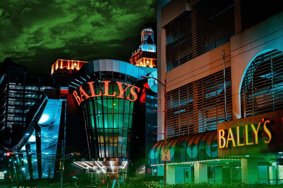 Glass covered multi level building reading BALLYS in neon red against a dark night.