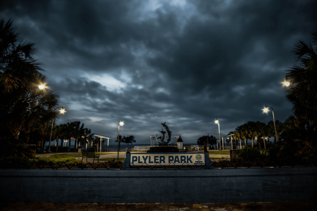 Plyler Park ghostly illuminated by overhead lamps and a grey/black night sky. Trees lurk on either side.
